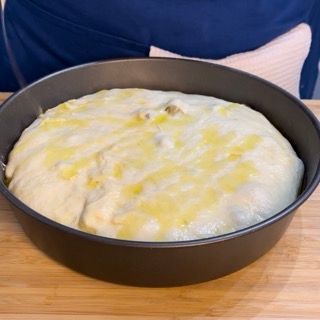 Una padella piena di pasta è appoggiata su un tavolo di legno.