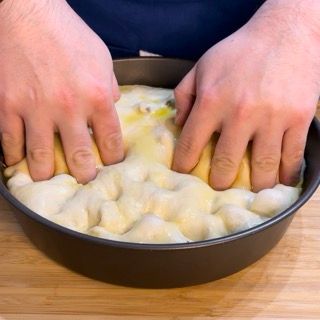 Una persona sta impastando l'impasto in una padella su un tavolo di legno.