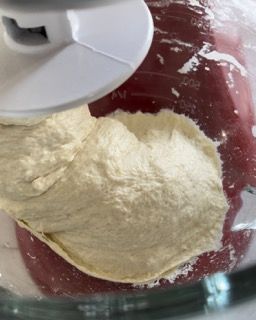 Un mixer sta impastando l'impasto in una ciotola di vetro