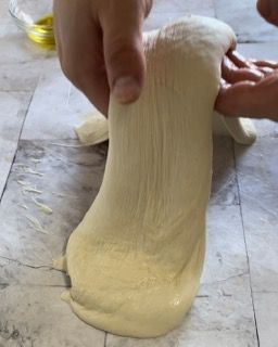 Una persona sta stendendo un pezzo di pasta su un tavolo
