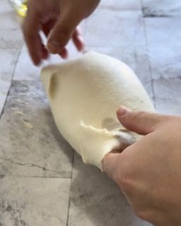 Una persona sta stendendo un pezzo di pasta su un tavolo
