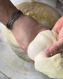 Una persona sta impastando un pezzo di pasta in una ciotola.