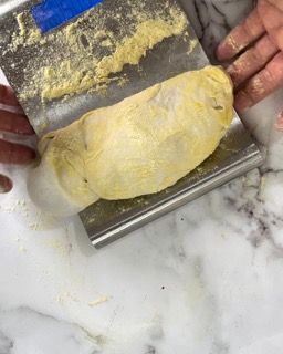 Una persona tiene una spatola sopra un pezzo di impasto.