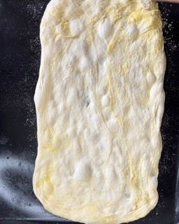 Un pezzo di pasta è appoggiato su una superficie nera.