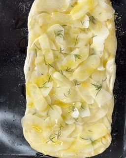 Una pizza con patate e aneto è appoggiata su un tavolo.