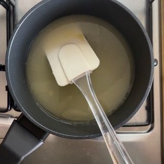 Una spatola è in una pentola piena di liquido sul fornello.