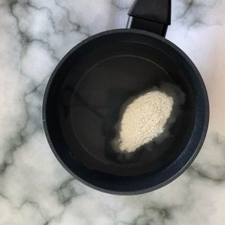 Una pentola nera piena di acqua e polvere su un tavolo.