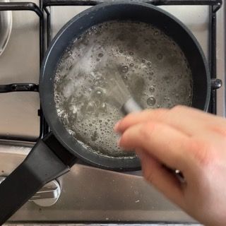 Una persona sta mescolando una pentola di acqua bollente su un fornello