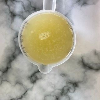 Su un tavolo c'è un misurino pieno di un liquido giallo.