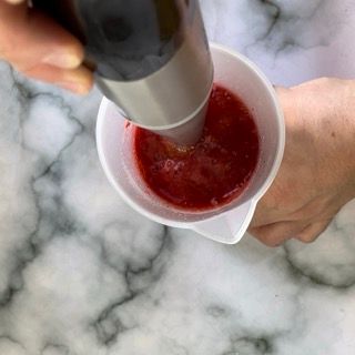 Una persona versa un liquido rosso in un misurino.