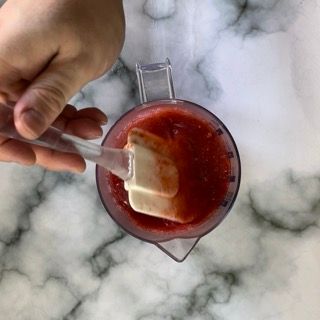 Una persona sta mescolando una salsa in una brocca con una spatola