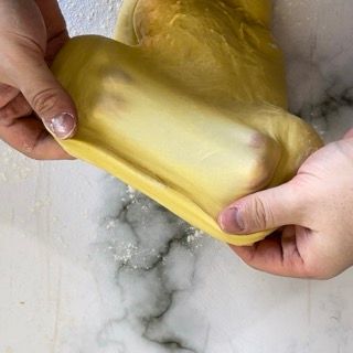 Una persona tiene in mano un pezzo di pasta.