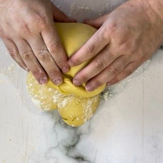 Una persona sta impastando una palla di pasta su un tavolo.