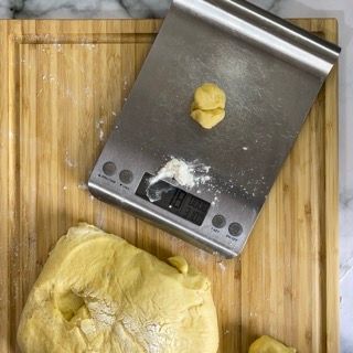 Una bilancia in acciaio inossidabile è appoggiata su un tagliere di legno.