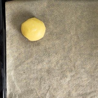 Una palla di pasta gialla è appoggiata su un pezzo di carta oleata.