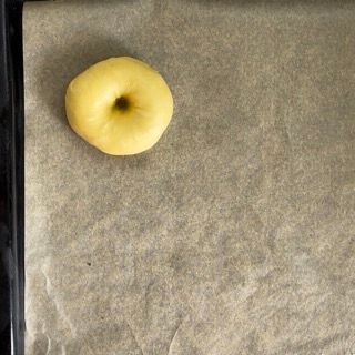 Una ciambella gialla è appoggiata su un pezzo di carta oleata.