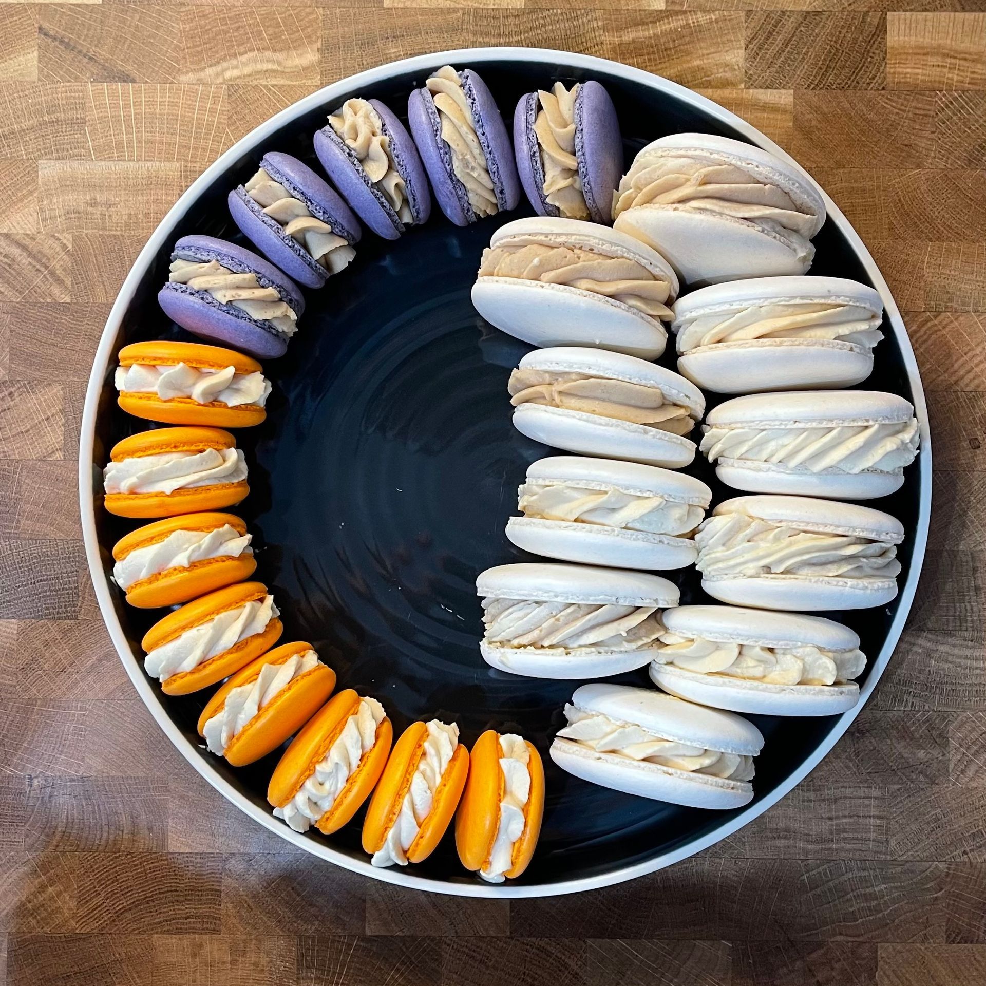 Un piatto nero sormontato da macarons viola e arancioni