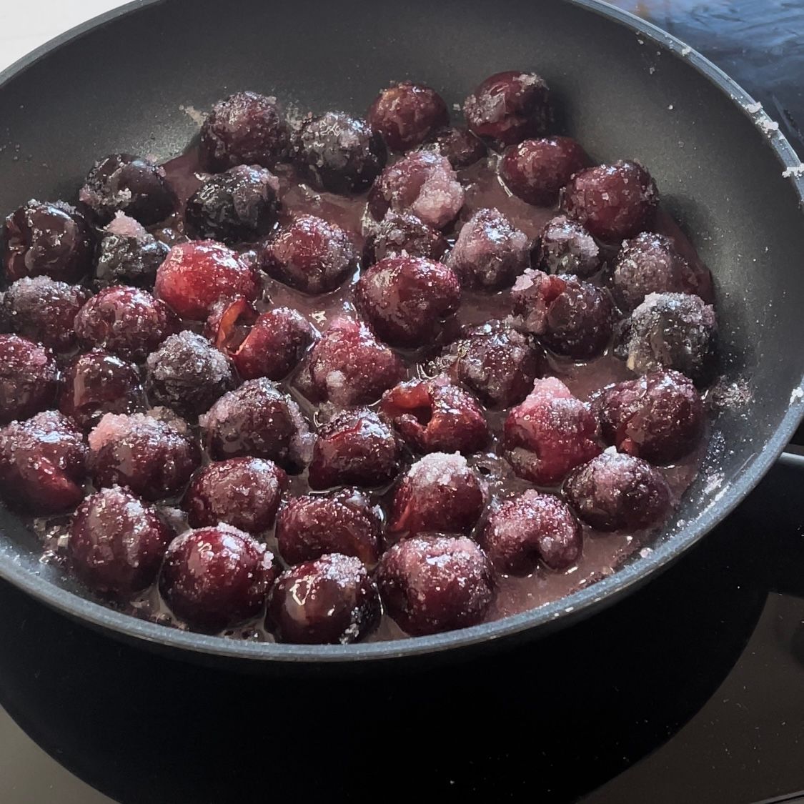 Una padella piena di ciliegie ricoperte di zucchero a velo