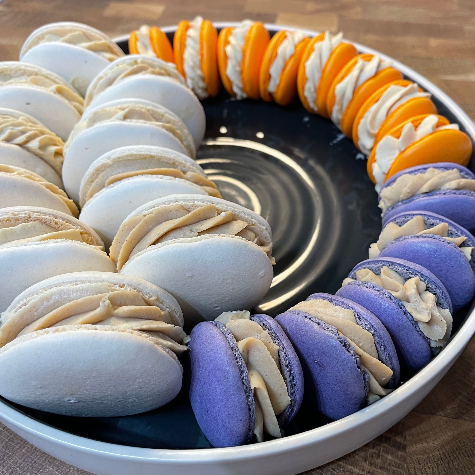 Un piatto di macarons con gusti diversi tra cui viola e arancione