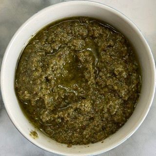 Una ciotola bianca piena di salsa verde su un tavolo