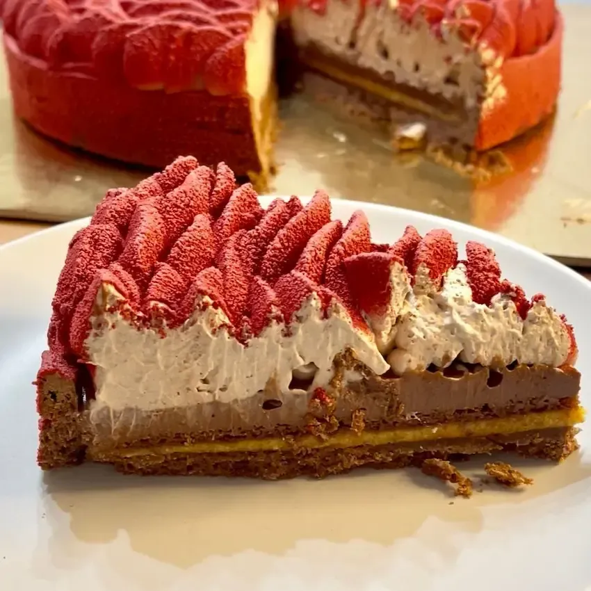 Fetta di crostata moderna al cioccolato che mostra i suoi strati perfetti: frolla al cacao, pralinato, biscuit, cremoso e ganache.