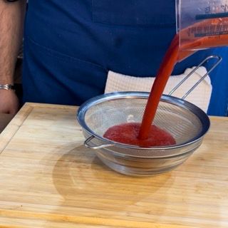 Un liquido rosso viene versato in un colino