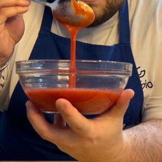 Un uomo con un grembiule sta versando la salsa in una ciotola