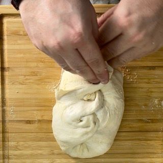 Una persona sta impastando l'impasto su un tagliere di legno.