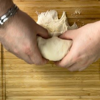 Una persona sta impastando l'impasto su un tagliere di legno.