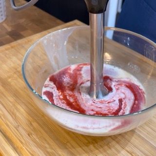 Un frullatore sta mescolando un liquido rosso in una ciotola di vetro