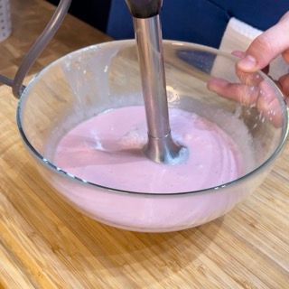 Una persona sta mescolando un liquido rosa in una ciotola di vetro