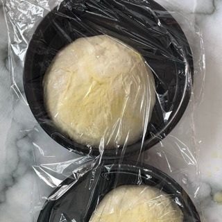 Due ciotole di impasto sono avvolte nella pellicola trasparente su un tavolo.