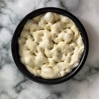 Una ciotola nera piena di una sostanza bianca su una superficie di marmo