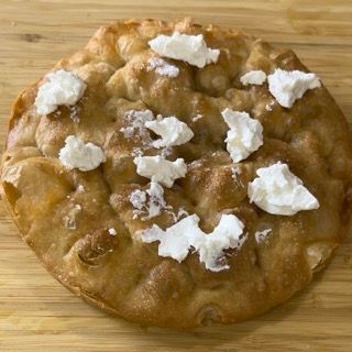 Un primo piano di una pizza con formaggio sopra su un tavolo di legno