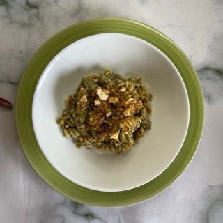 Una ciotola di pasta è su un piatto verde