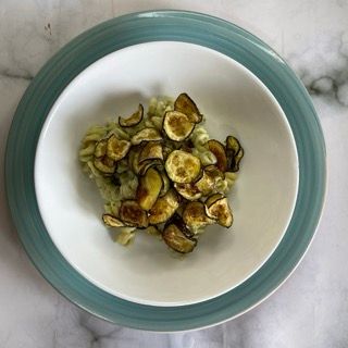 Una ciotola di pasta e zucchine su un piatto blu