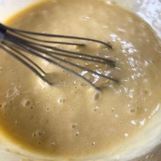 Un primo piano di una frusta in una ciotola di liquido