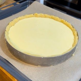 Una cheesecake è appoggiata su un vassoio sopra un pezzo di carta oleata.