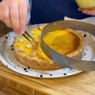 Una persona sta tagliando una torta con delle pinzette su un piatto.