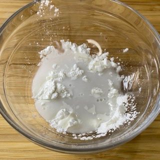 Una ciotola di vetro piena di liquido bianco e zucchero a velo