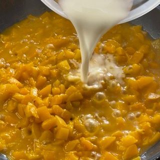 Una persona sta versando il latte in una pentola di cibo.