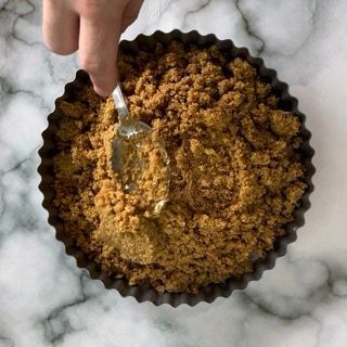 Una persona tiene in mano un cucchiaio in una ciotola di zucchero di canna