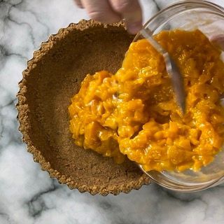 Una persona sta versando la salsa all'arancia nella pasta di una torta.