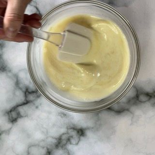 Una persona tiene una spatola sopra una ciotola di salsa.