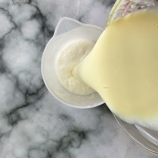 Un liquido giallo viene versato in un misurino su un tavolo.