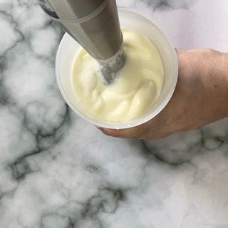 Una persona versa la maionese in una tazza con una sac à poche.