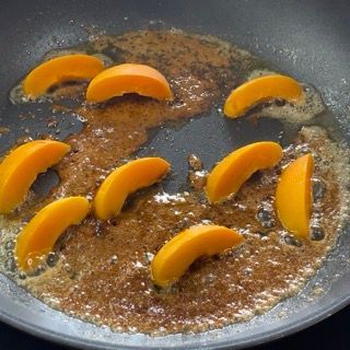 Le pesche tagliate a fette vengono cotte in una padella