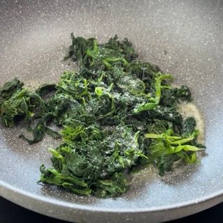 Gli spinaci vengono cotti in una padella sul fornello.