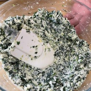 Una ciotola di spinaci e formaggio con una spatola dentro