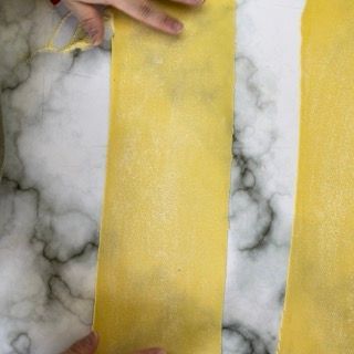 Una persona tiene in mano un pezzo di carta gialla su una superficie di marmo.